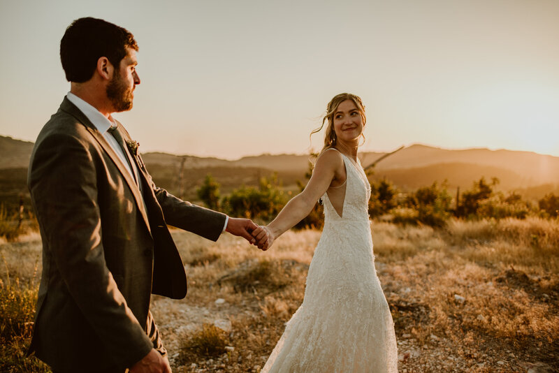 Newlyweds sharing a glance as they explore a hilltop over Sonoma Valley at golden hour sunset on their wedding day
