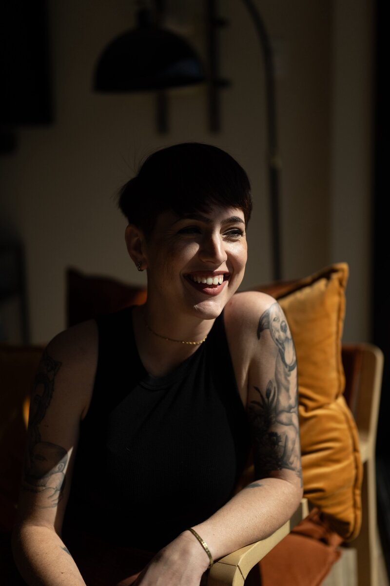 woman sits in chair smiling