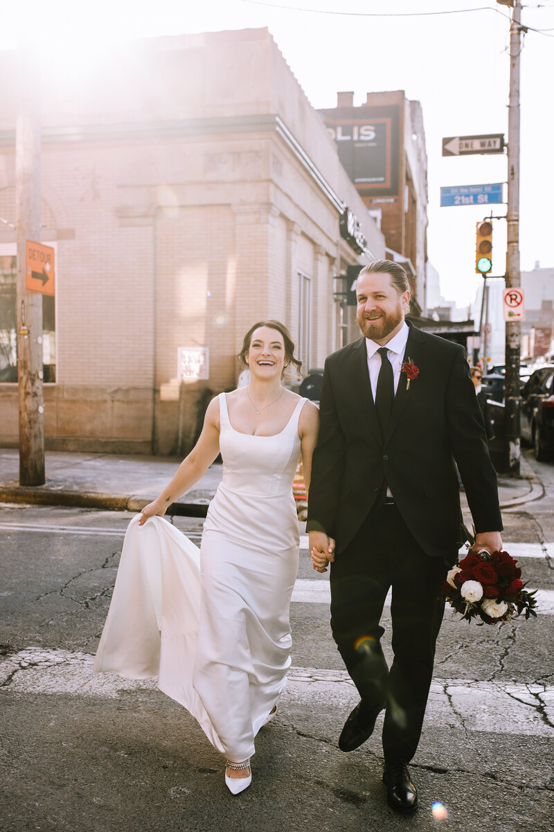 Married couple running through sunset in the streets of the strip district in Pittsburgh. 