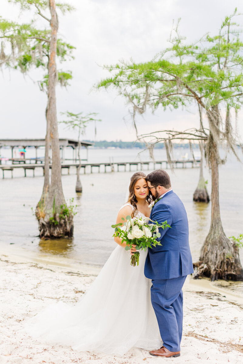 a newlywed couple embracing by a lake