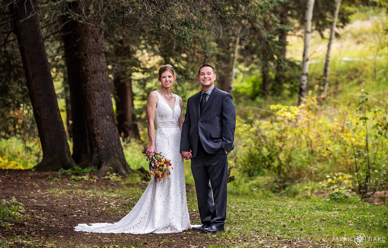 Couple Holds Hands in the Forest at their Beaver Ranch Wedding in Conifer Colorado