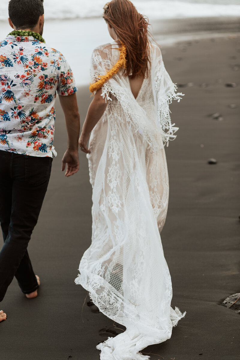 Bride and groom walking on a black sand beach for their elopement on the big island of hawaii