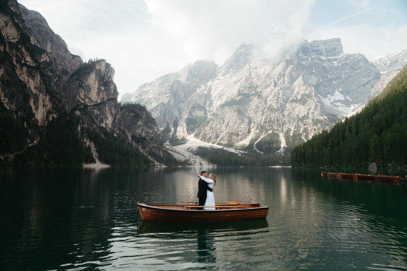 Dolomites Elopement with bride and groom standing in a rowboat on Lago di Braies with mountains in the back