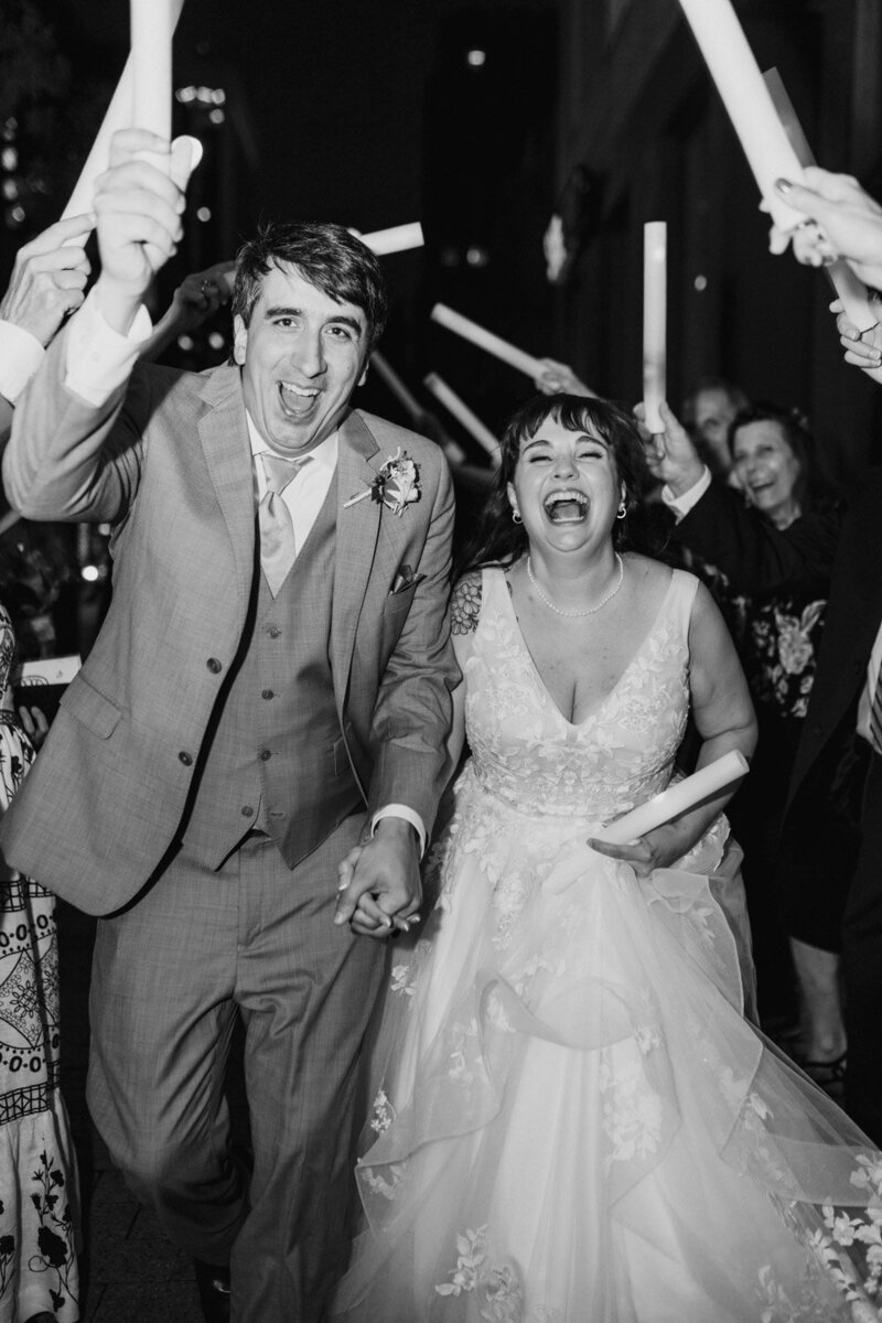 Bride and groom joyfully exiting with glow sticks