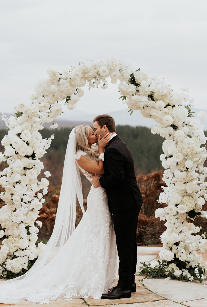 white flowers with a couple embracing in front of the mountain backdrop
