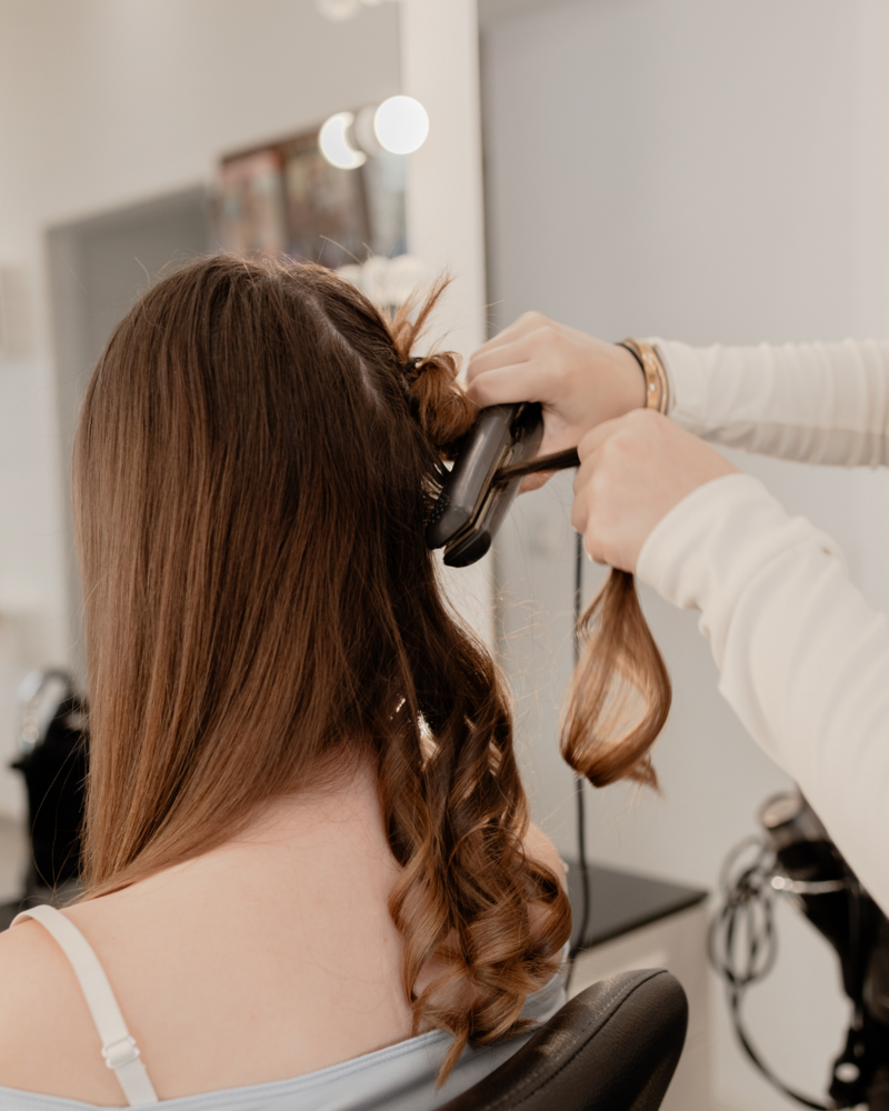 Friseurin lockt einem Mädchen die Haare