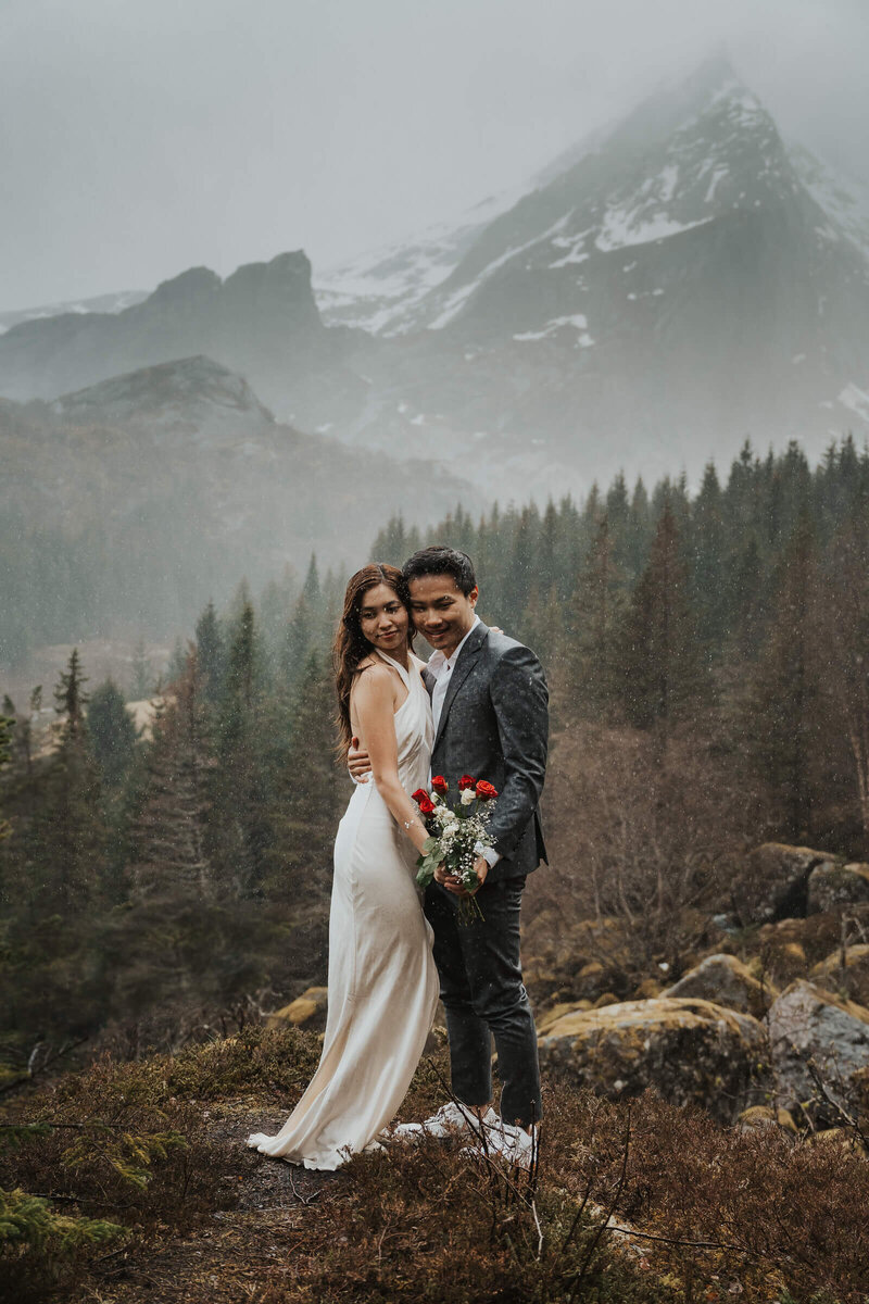Wedding couple embracing in the rain on a mountain in Lofoten Norway