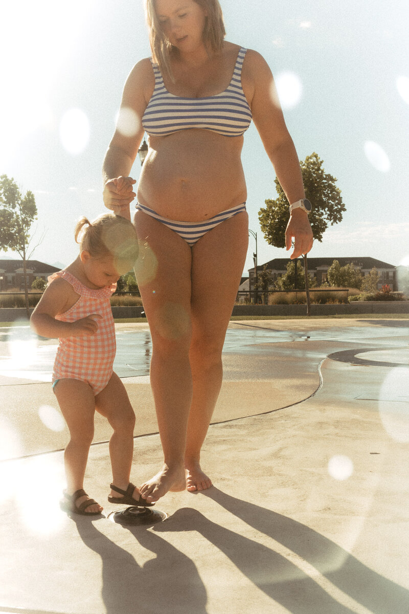 Mom and daughter in swim suits at a Park City, UT splash pad.