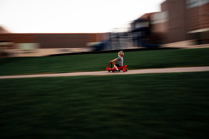 Toddler cruising down hill on riding toy