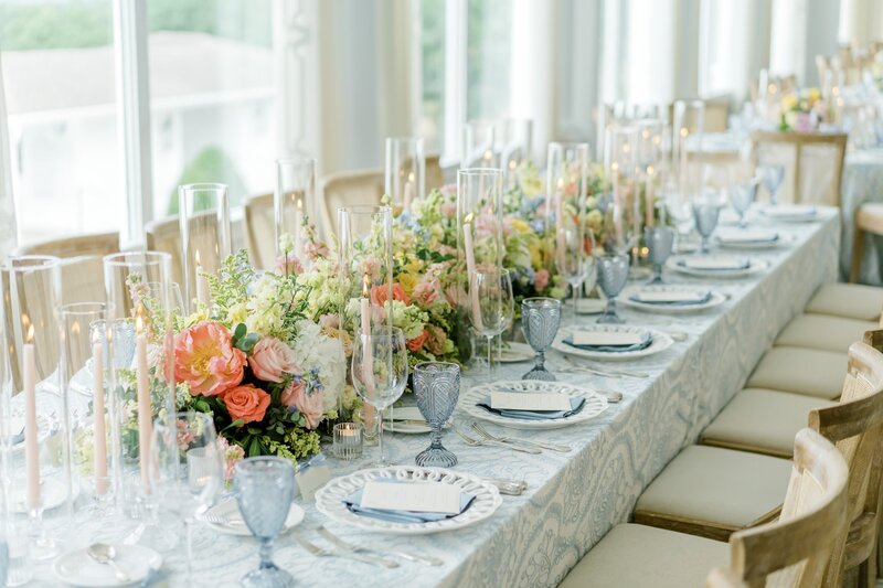 Long table decorated with pastel flowers and candles.