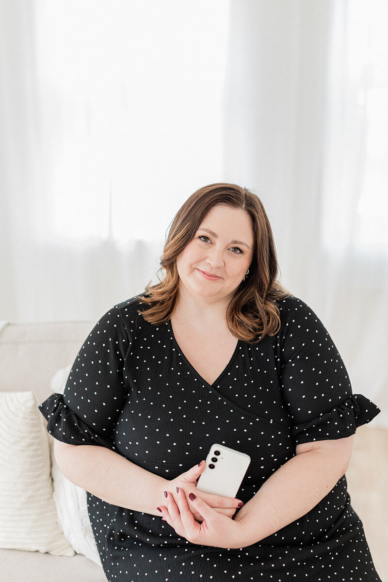 Woman in purple dress smiling at camera holding ipad