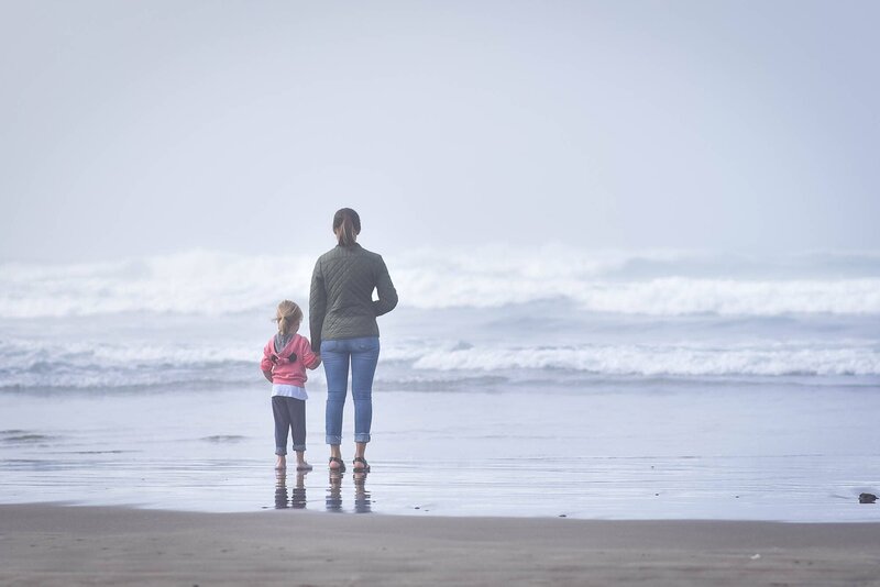 Colorado wedding and boudoir photographer holding hands with daughter in front of the ocean