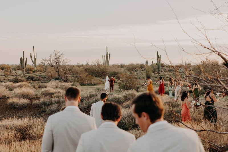 Candid photo of wedding party walking towards the desert