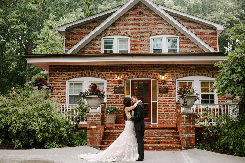 Bride and Groom kissing in front of old brick home on their wedding day