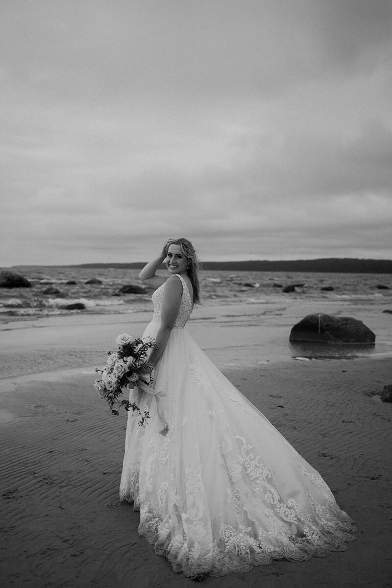 black and white image bride standing on beach