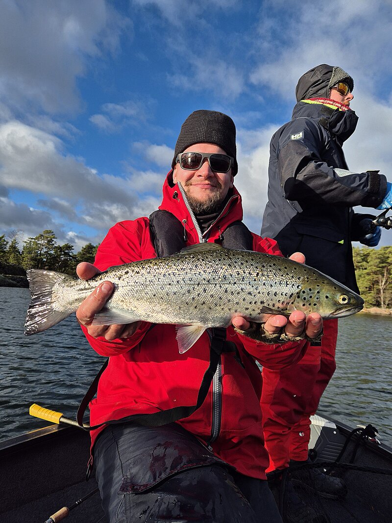Asiakas taimenen heittokalastusretkellä esittelemässä isoa taimenta, jonka hän on kalastanut