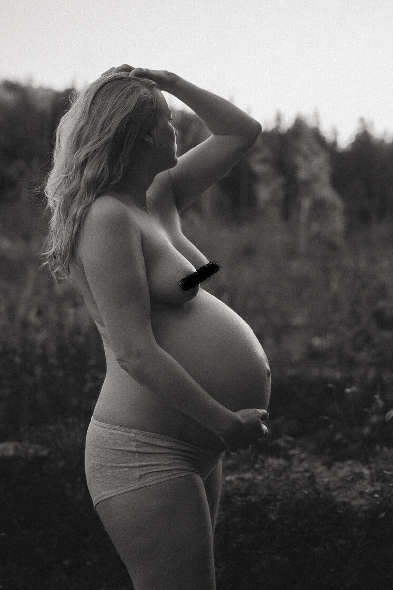 Hudnära svartvit bild på en gravid kvinna på en gravidfotografering i Ljusdal.