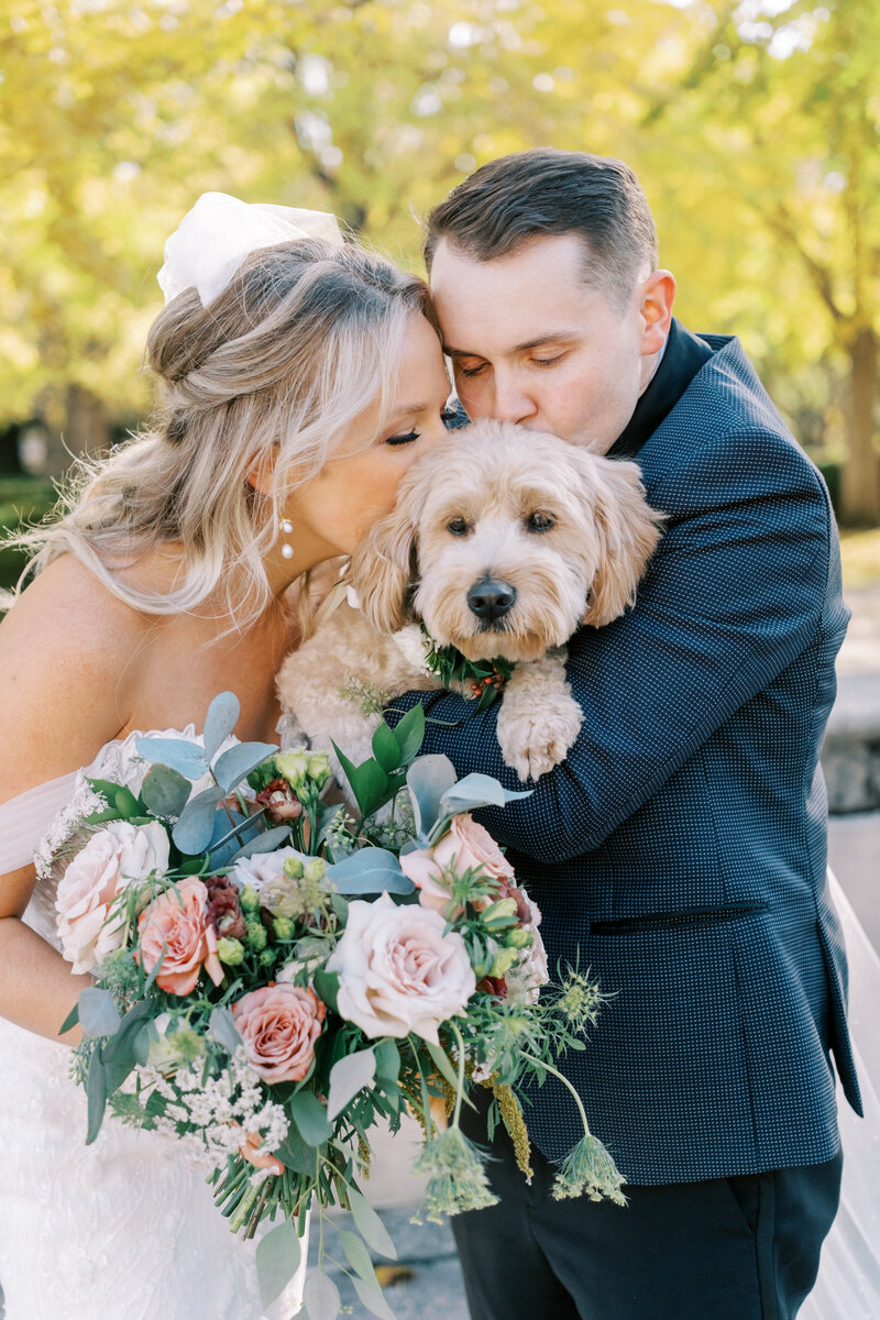 bride and groom kiss dog during fall wedding day in Kansas City, Missouri