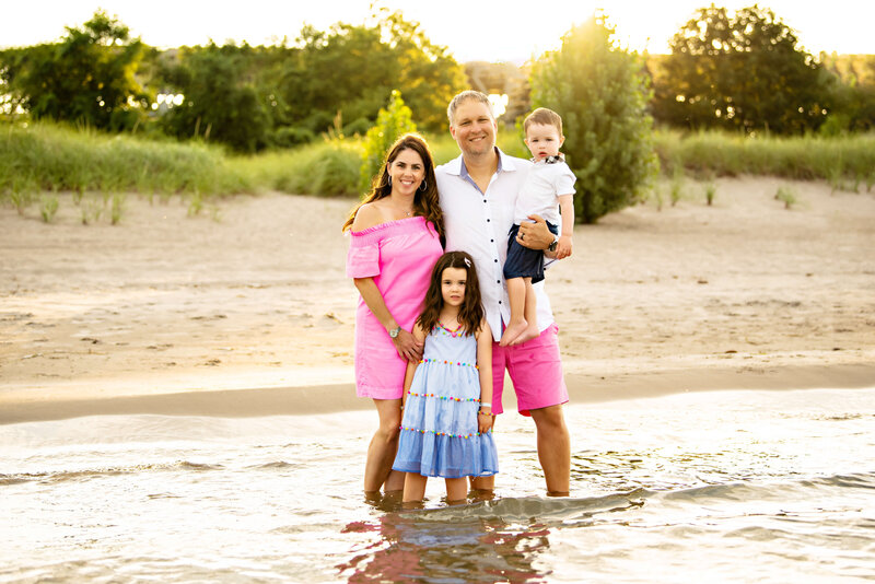 mom and dad standing the in the water at the beach with their son and daughter for their outdoor family photography session.