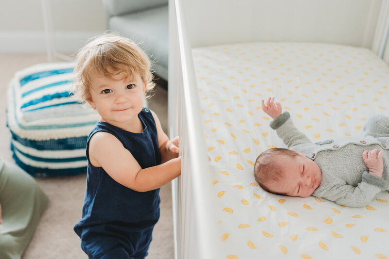 brother looking at baby brother in a crib