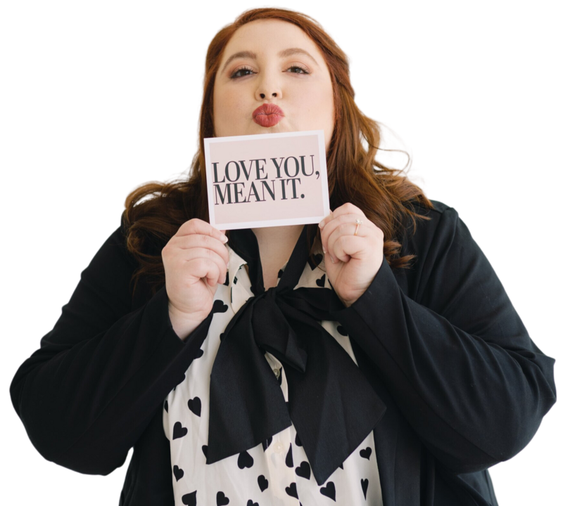 auburn haired woman making kiss face and holding a card that says: love you, mean it