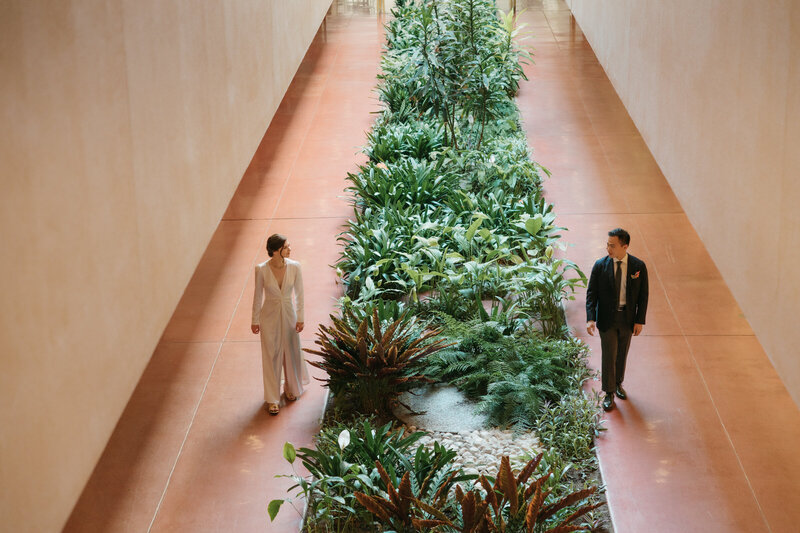 Couple walking through indoor garden hallway at Marin Civic Center elopement.