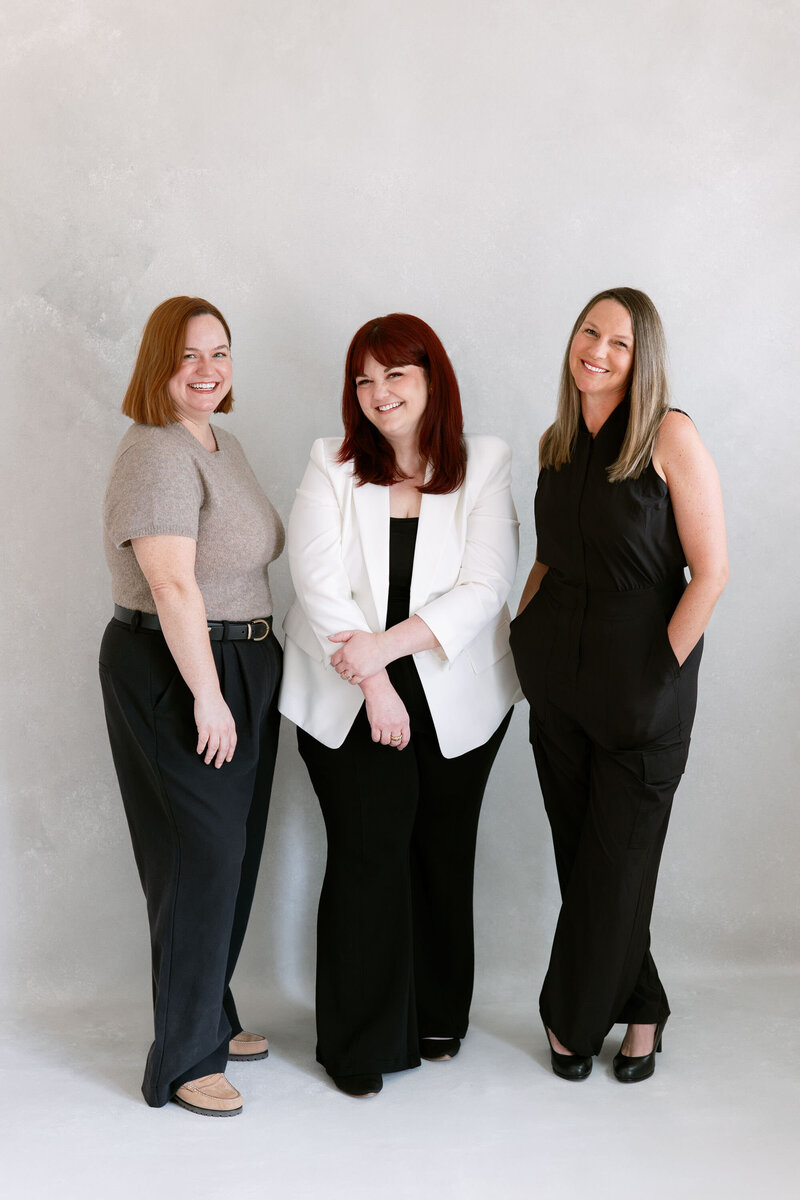 3 women in wedding photography team embrace