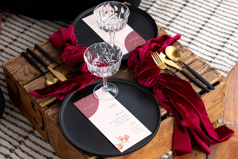 Wedding menus and place cards in pink card and held together with a teardrop clasp, sitting on a red romantic table setting