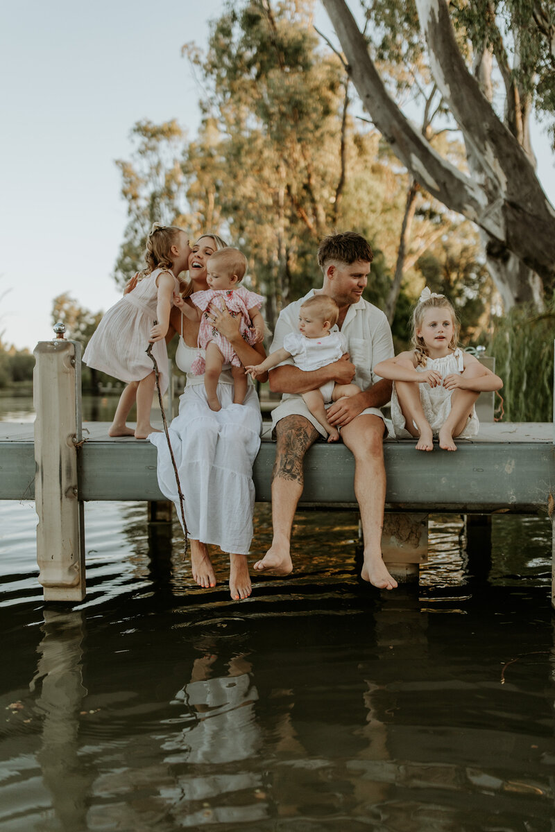  "Family of four laughing together in a sunlit field, captured by Kayla Frizzell Photography.