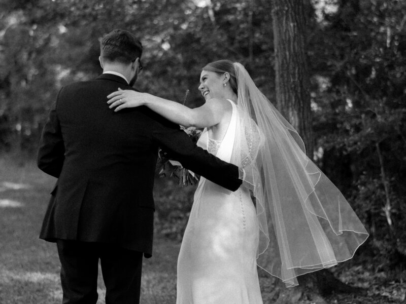 Black and white image of bride and groom walking with arms around each other