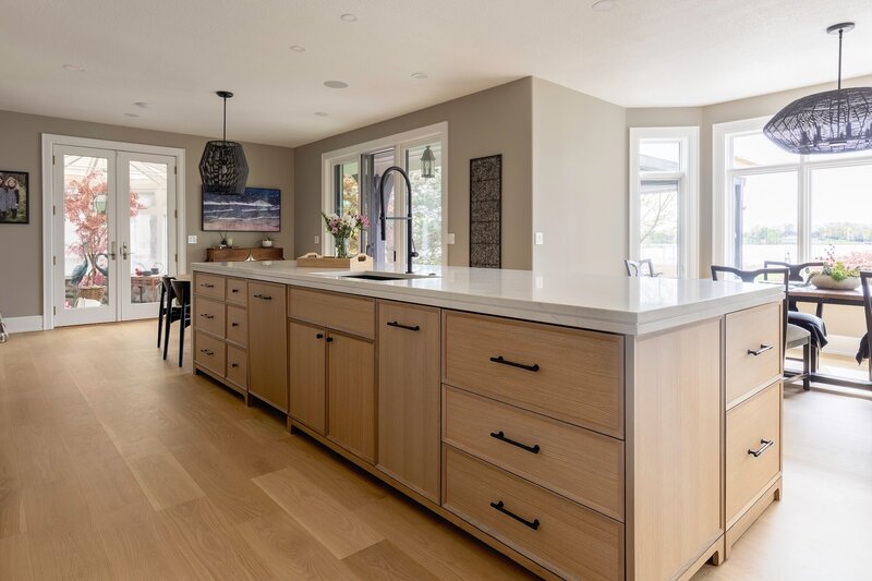 A mix of white and light wood cabinets with sleek black fixtures and white counter tops.