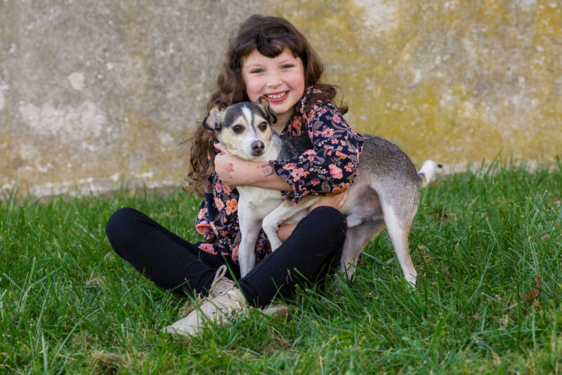 A little girl hugging her dog tightly during a heartwarming mini session in the Greater Philadelphia area.