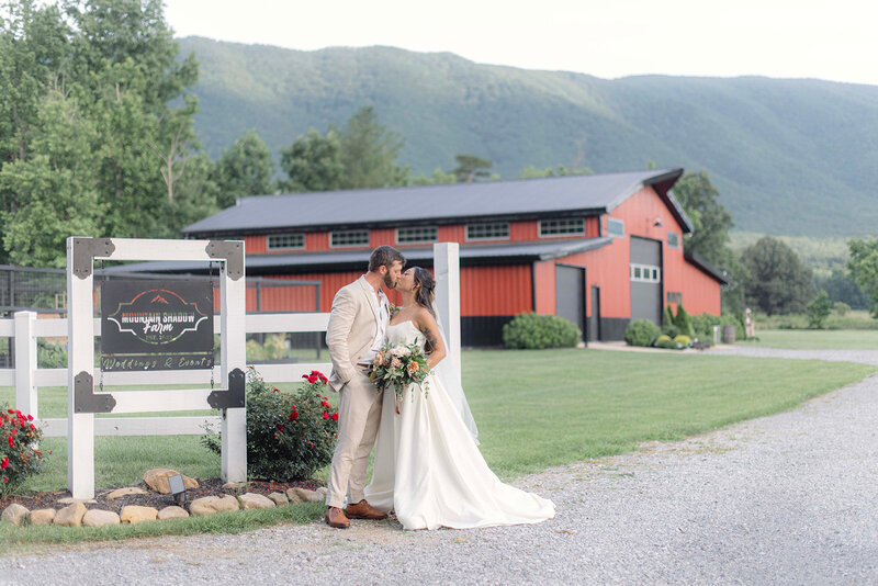 Couple poses for wedding photos in front of the rustic barn at Mountain Shadow Farms in Greeneville, TN