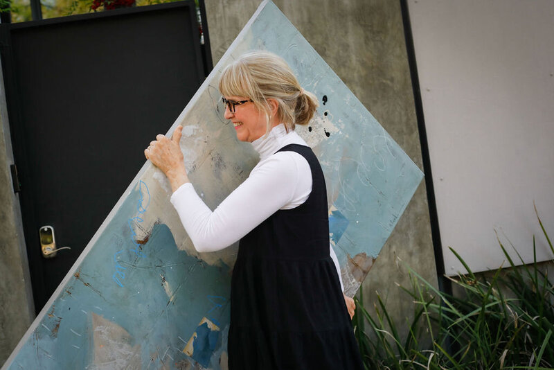 Adele walking in carrying large abstract painting