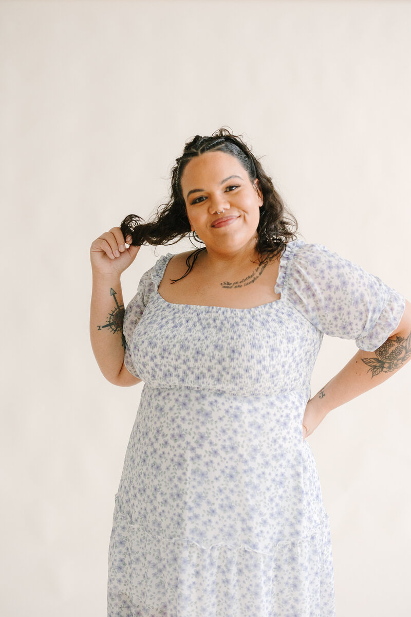 A person smiling and twirling her hair in one hand