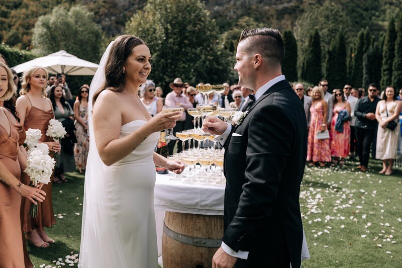 newly married couple cheers champagne glasses in front of champagne tower at the winehouse in queenstown