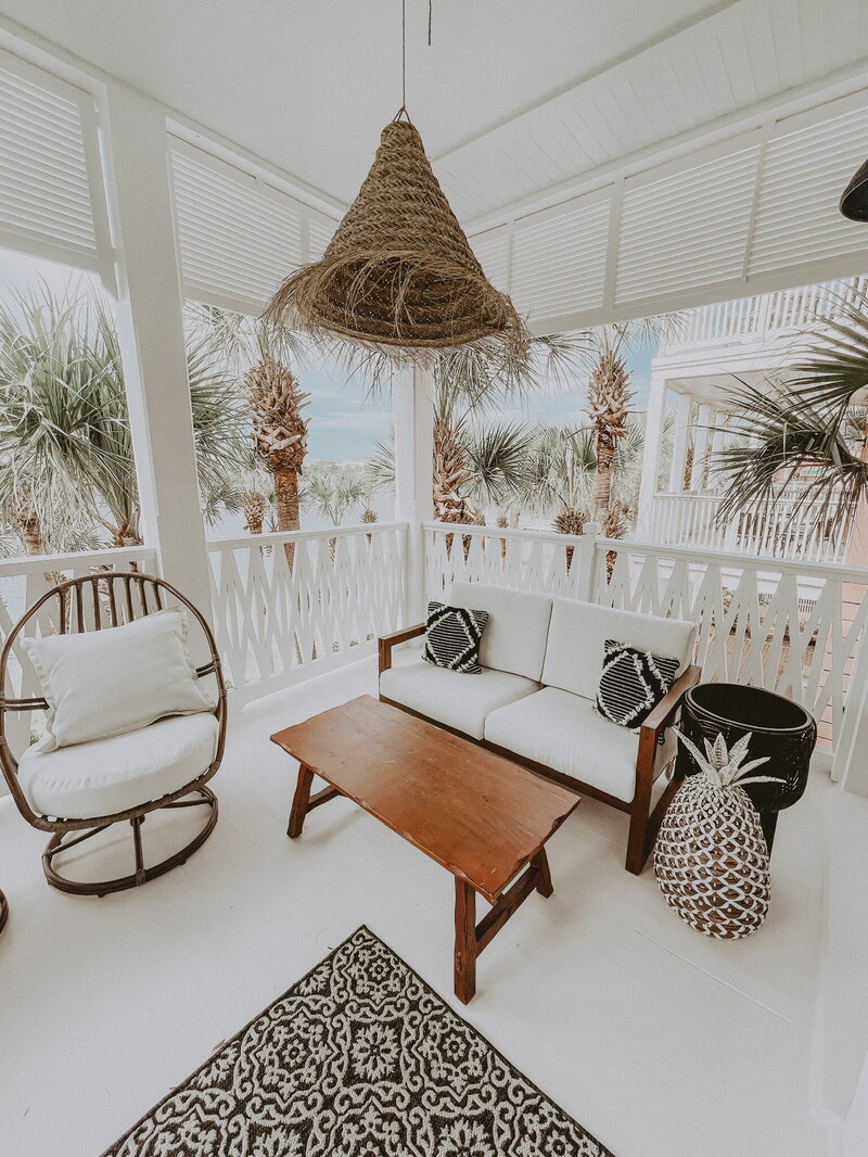 white porch with rattan chandelier and wooden patio furniture