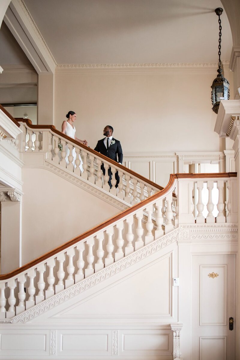 Editorial picture of an interracial wedding couple walking down an elegant staircase at the Cairwood Estate.
