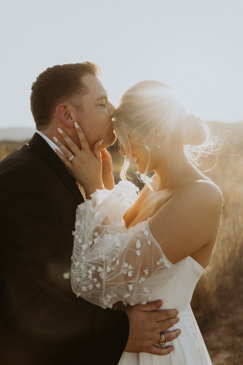 groom kissing brides forehead during outdoor elopement in montana