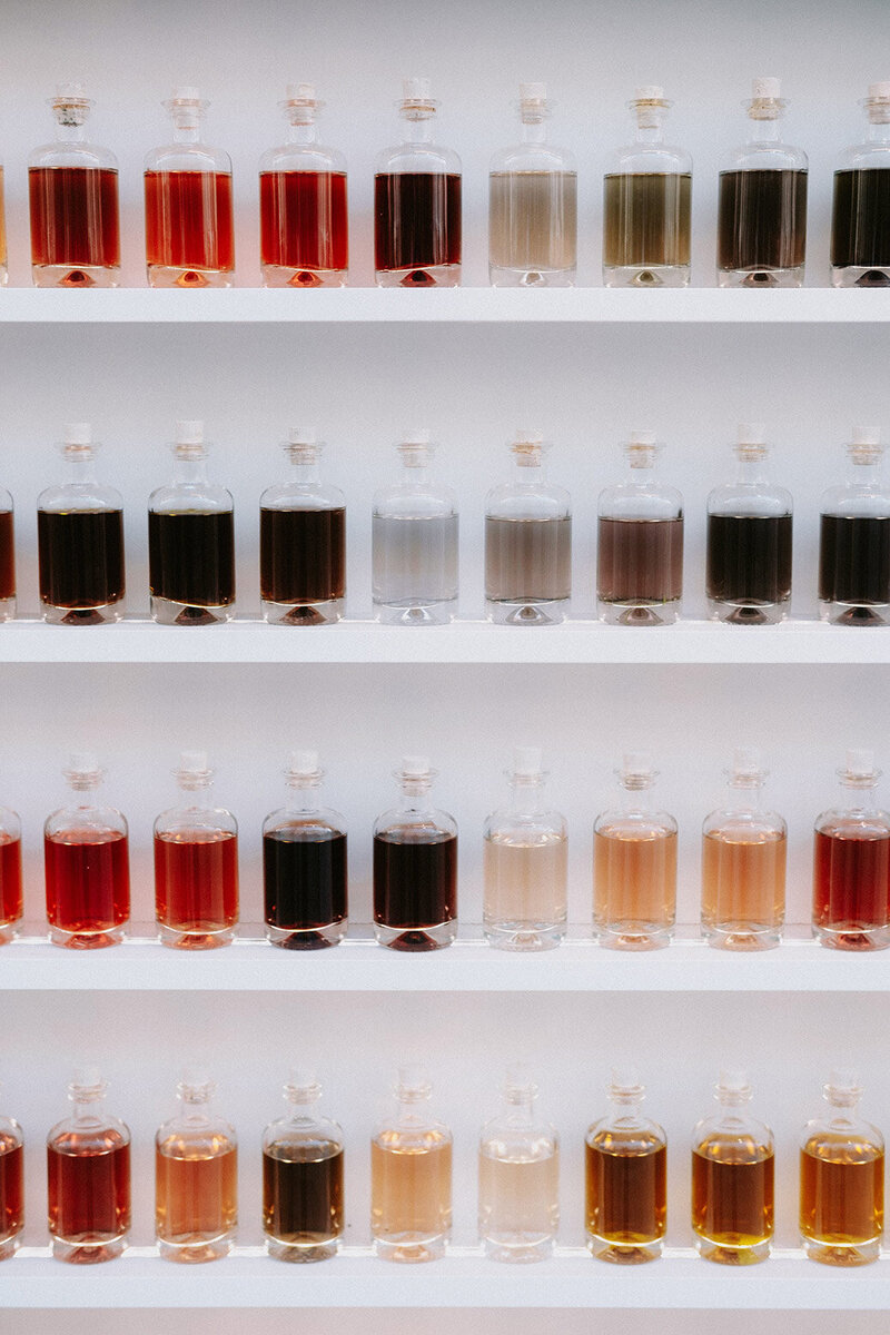 tonic bottles of various colors  lined up on  three shelves