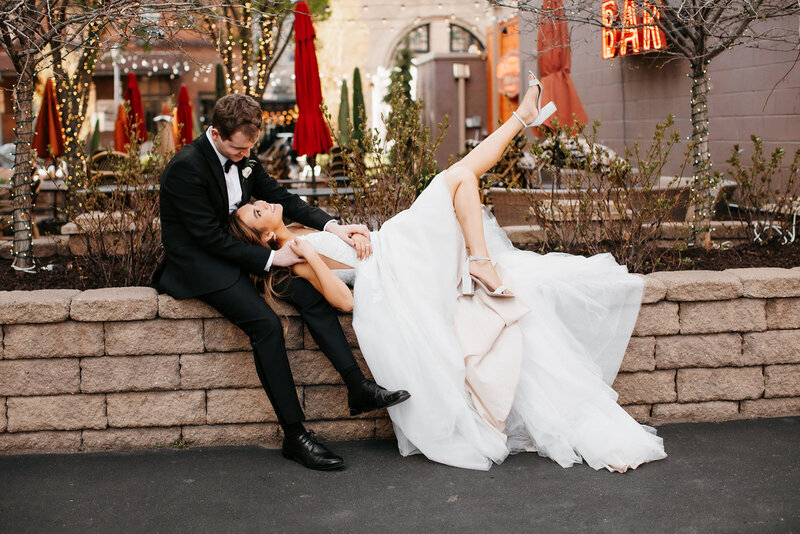 Bride laying with her head in groom's lap on a stone wall with her legs up