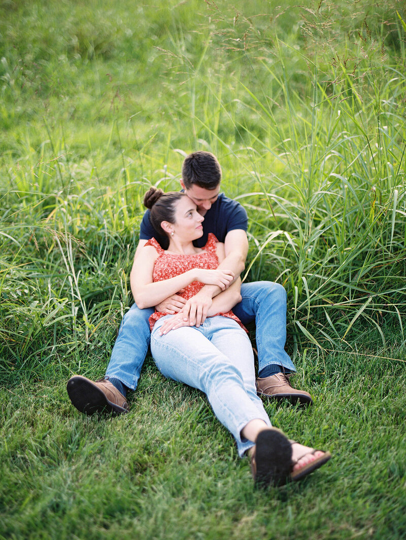 Couple sits in a grass field at their private estate.