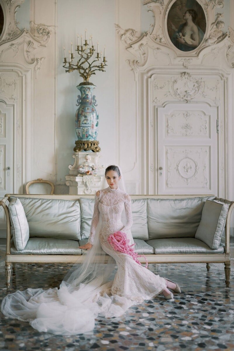  Bridal portrait during a villa Sola Cabiati wedding, bride sitting on an antique sofa in the Stucco Room, photographed by luxury destination wedding photographer Andreas K. Georgiou  