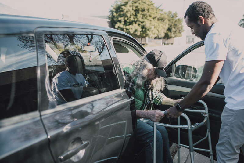 Older woman getting out of car with walker and assistance