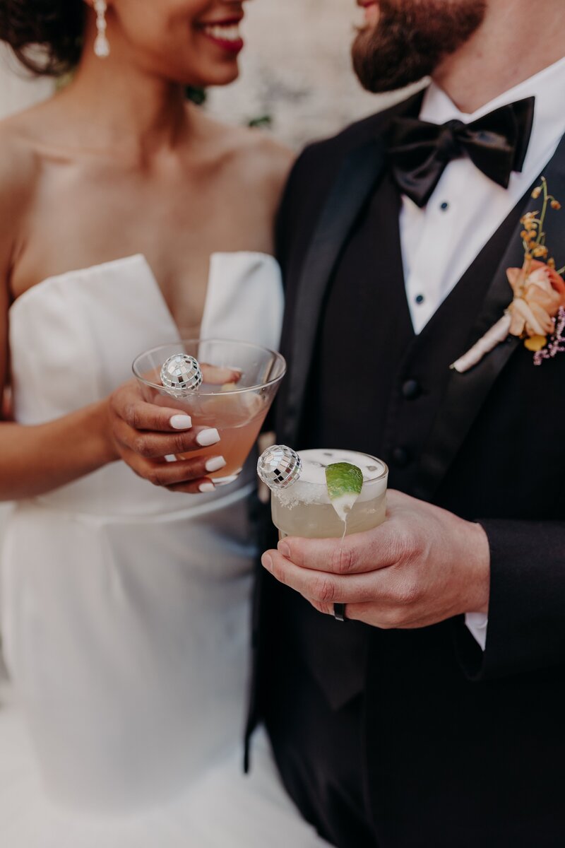 Bride and groom clink glasses with disco ball stir sticks