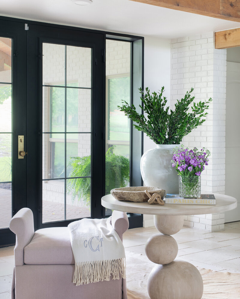 Black french door into home with white brick walls and luxury decor