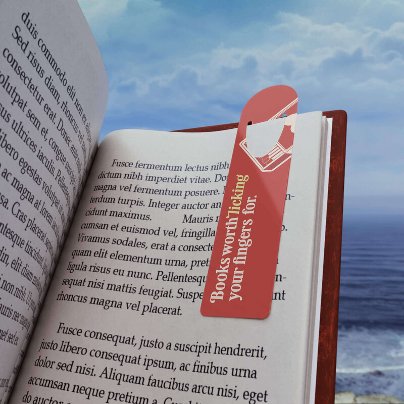 A cream and red bookmark that says Books worth licking your fingers for in a book.