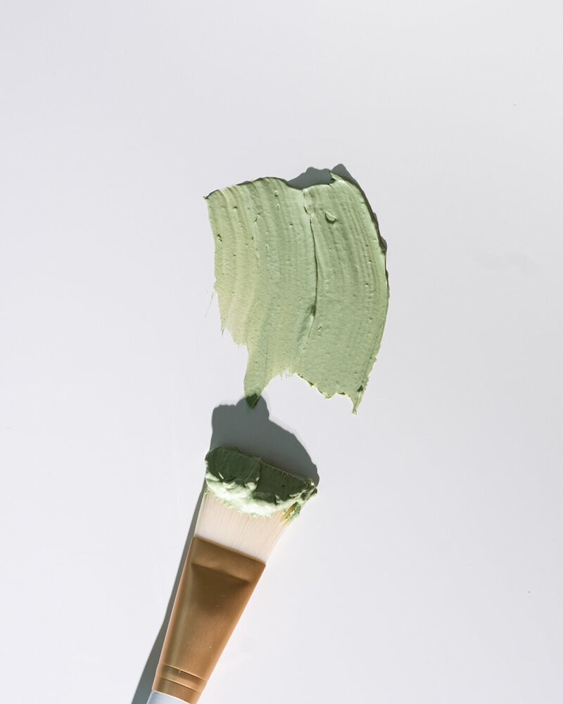 Close-up photo of skincare green mask smeared with an application brush. 