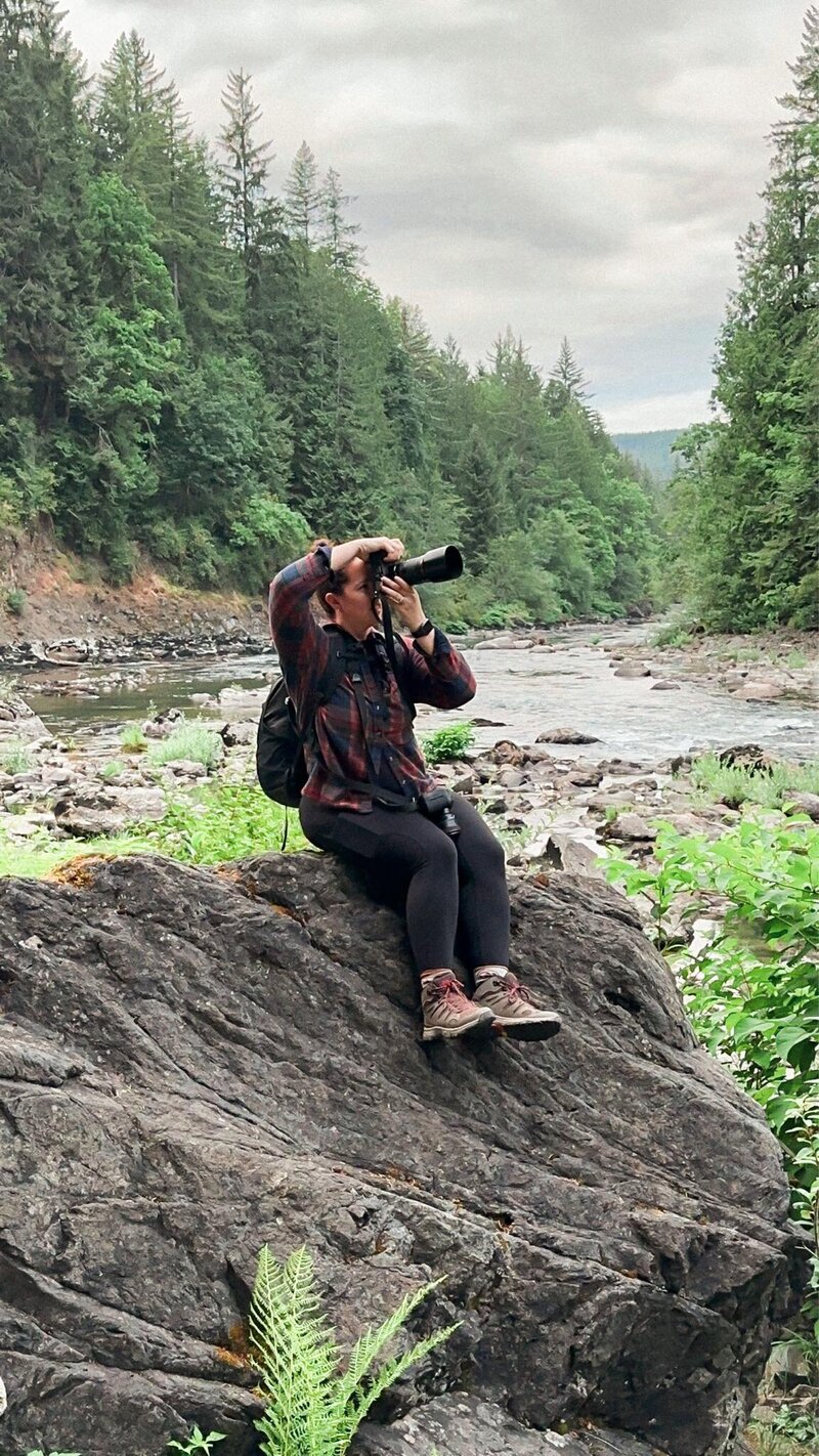 Jess Collins standing on a beach holding her cameras