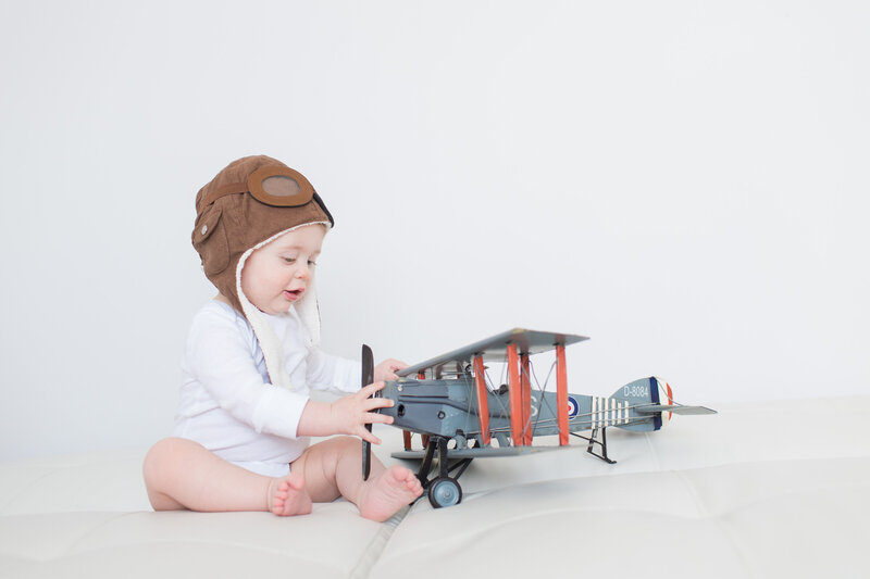 Child playing with a toy airplane wearing a pilot's hat